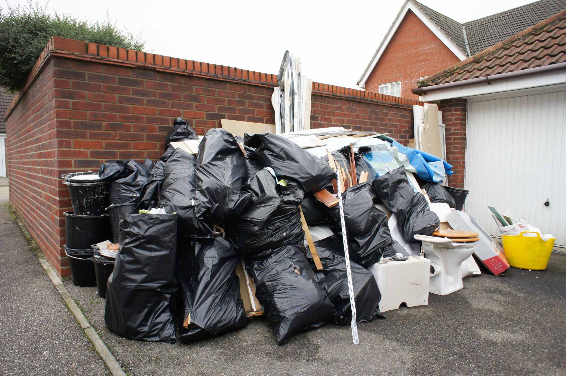 Pile of household junk: garbage bags, drywall, an old toilet, boxes, etc