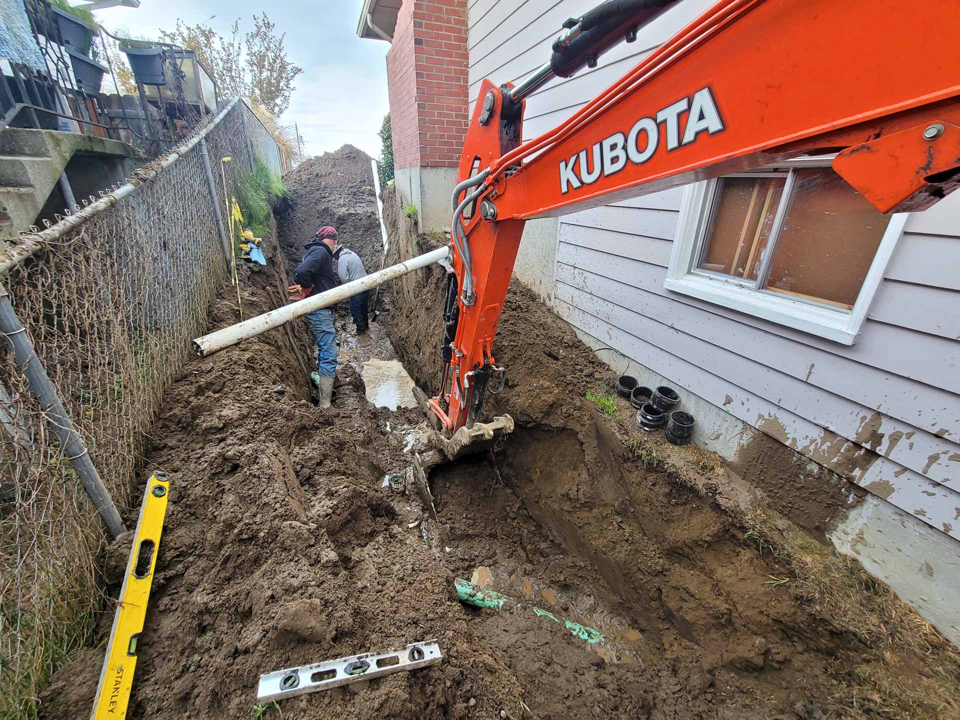 Workers from Salish Excavation and Trucking LLC in trench next to house