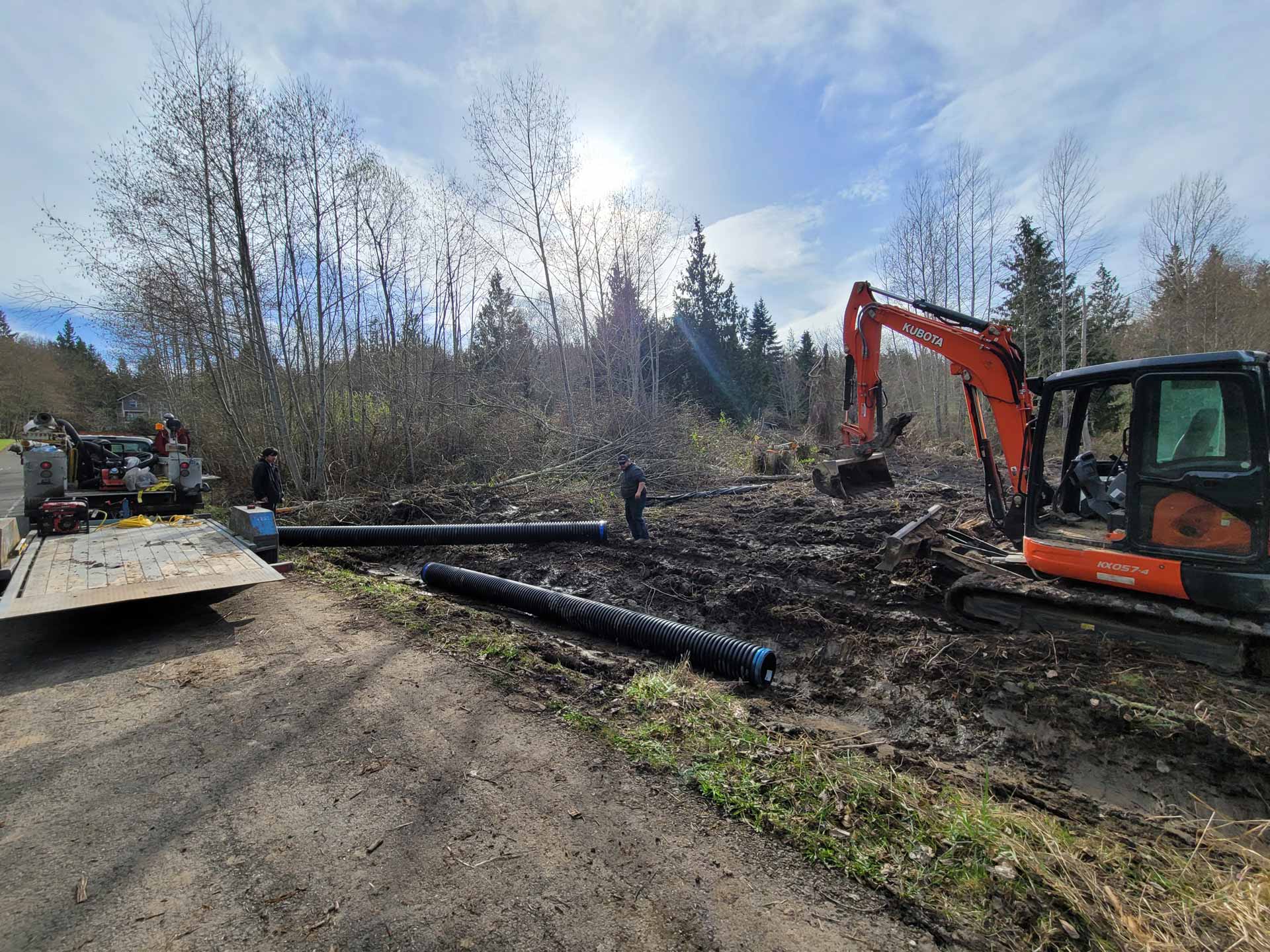 Workers from Salish Excavation and Trucking LLC laying corrugated pipes in trench